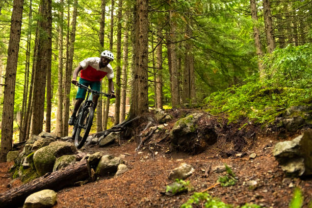 Male mountain biker riding in a forest African American athlete riding a mountain bike. Best biking destinations in North America. Living an active lifestyle. mountain bike stock pictures, royalty-free photos & images