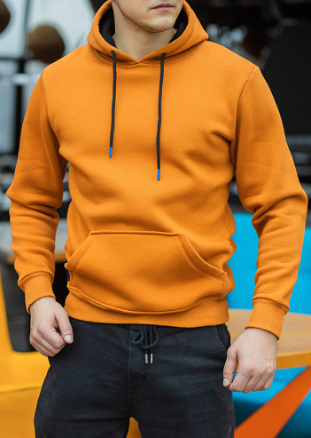 Handsome attractive European muscular man in orange hoodie