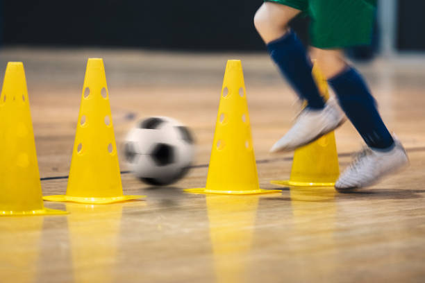istock Player Practicing Indoor Soccer Dribbling Skills Running Between Yellow Training Cones. Futsal Training Unit for Youth Team 1301052578