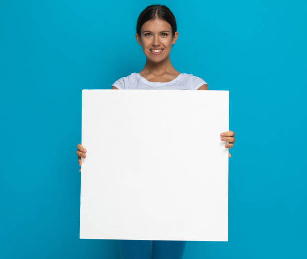 istock happy casual woman presenting her billboard at the camera 1301057082