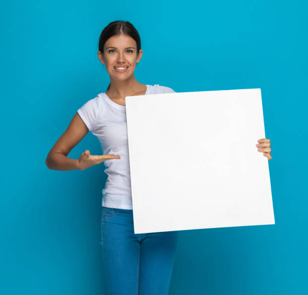 istock young casual woman presenting her blank billboard with a smile 1301057161