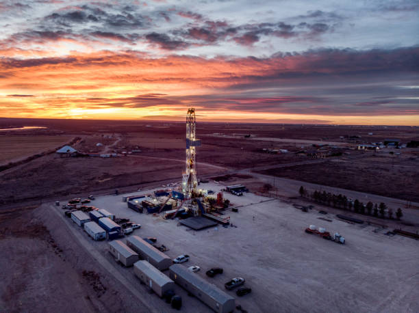 drohnenansicht eines öl- oder gasbohrers fracking rig pad, wenn die sonne in new mexico untergeht - fracking stock-fotos und bilder