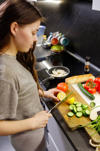 istock Young woman cut lemon for preparing salad in kitchen, close up 1301057291