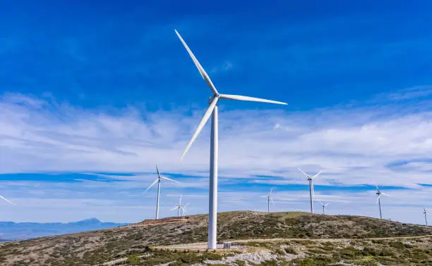 Wind turbines on the hill, Wind farm. Green ecological power energy generation. Alternative energy plant, blue cloudy sky, Greece