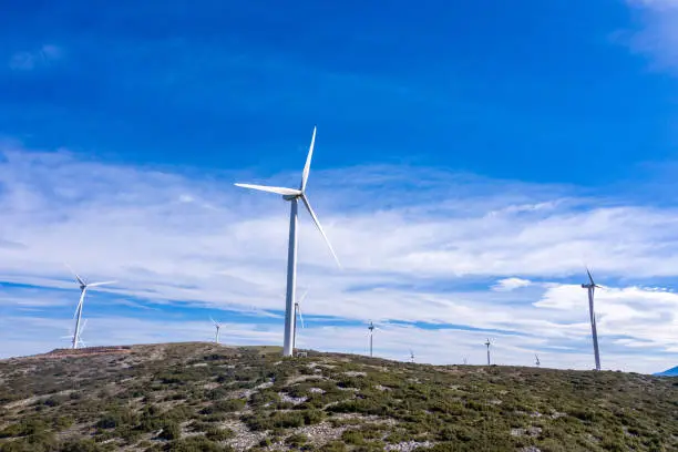 Wind farm. Wind turbines on the hill, Green ecological power energy generation. Alternative energy plant, blue cloudy sky, Greece