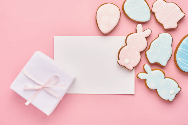 istock Easter greeting card with colorful rabbits, eggs, chickens and carrots gingerbread cookies on pink background with copy space. Mock up. Banner. Top view. 1301060086