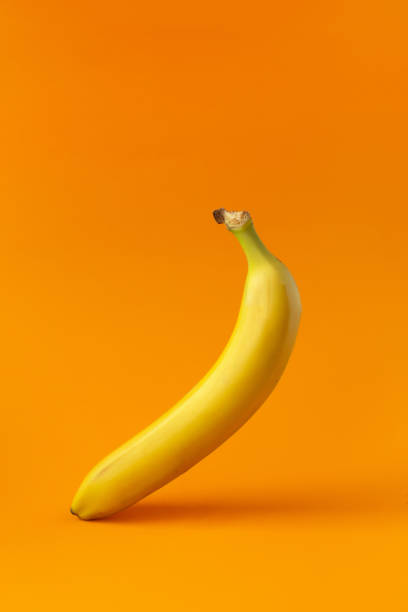 istock One yellow ripe banana isolated on orange background. 1301060260