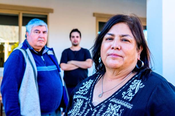 hispanic family, mother, father and son posing outside their backyard looking at the camera - common serious couple men imagens e fotografias de stock