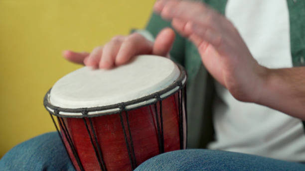 istock Male hands tapping djembe, bongo in rhythm. Musical handmade instruments 1301062101