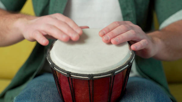 istock Male hands tapping djembe, bongo in rhythm. Musical handmade instruments 1301062128