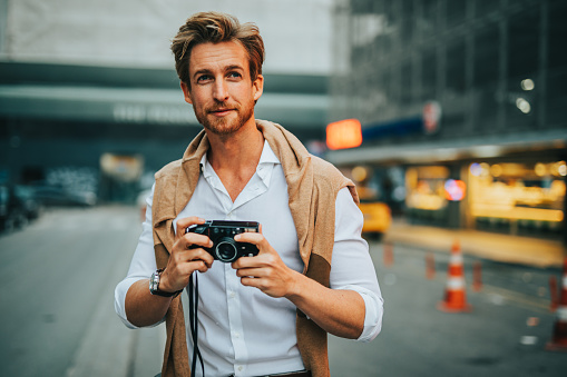 Young man standing on the street and holding camera