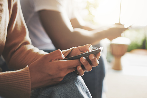 Closeup shot of an unrecognisable couple using their digital devices at home