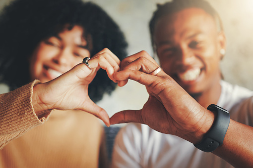 Closeup shot of a young couple making a heart shape with their hands