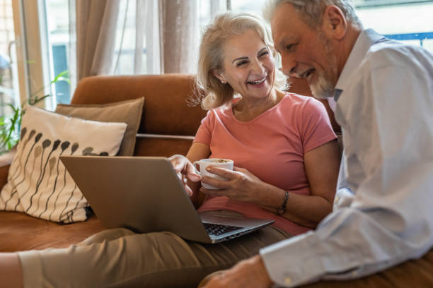 istock Happy senior couple at home, using laptop 1301068043