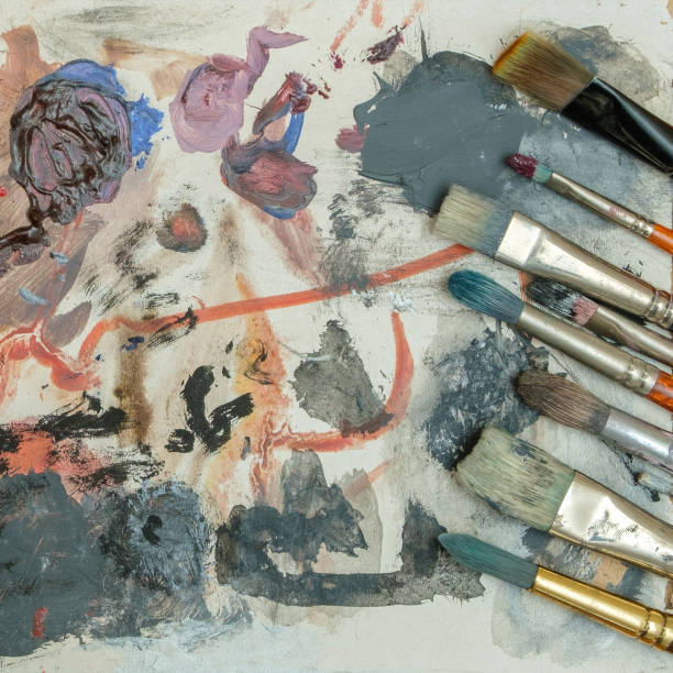 istock Paint brushes on a palette with dried paints. 1301068184