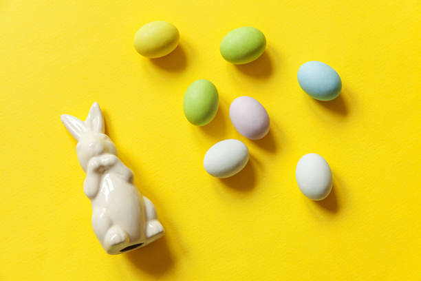 istock Happy Easter concept. Preparation for holiday. Easter candy chocolate eggs sweets and bunny toy isolated on trendy yellow background. Simple minimalism flat lay top view copy space 1301068212
