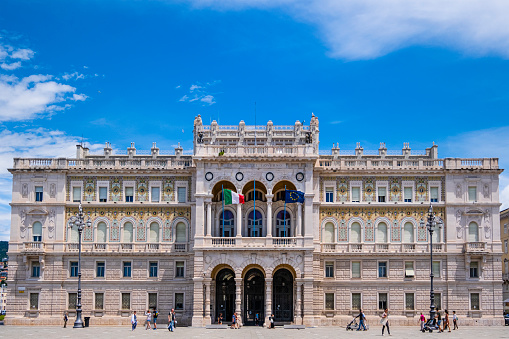 Tourists visiting Piazza Unità d'Italia, the main square of Trieste, surrounded by numerous palaces and public buildings, such as the Government House in the picture.