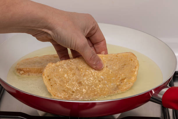 istock Woman's hand and frying pan with oil preparing fried bread with egg and flour (Torrijas). Typical Spanish Easter sweet. Traditional home cooking concept. Horizontal photography and selective focus 1301071264