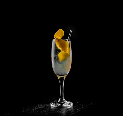 French 75 cocktail in a champagne flute on black background