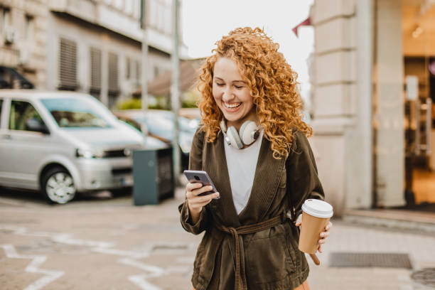 istock Young woman is using mobile phone on the move and holing reusable coffee cup 1301073550