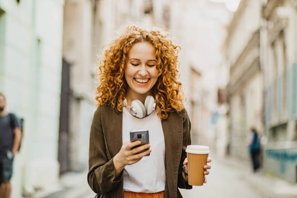 istock Young woman is using mobile phone on the move and holing reusable coffee cup 1301073704