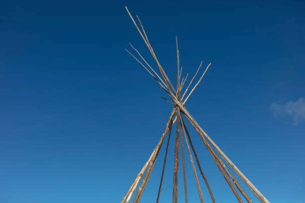uno sguardo in cima a una struttura tipi (teepee) in disarti, contro un cielo blu. - north american tribal culture teepee winter canada foto e immagini stock