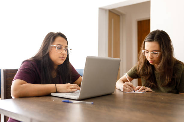 istock Young woman using laptop and her girlfriend writing notes 1301076211