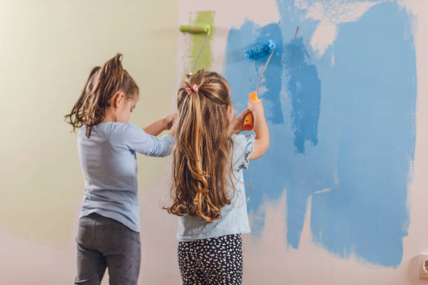 istock Two little girls applying paint on the wall with paint rollers 1301078440