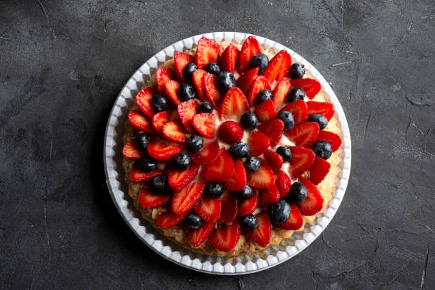 Sweet indulgence. Delicious strawberry tart with fresh blueberry on wooden rustic table. tart dessert stock pictures, royalty-free photos & images