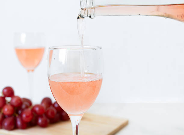 wino różane wlewa się do szklanki z butelki - champagne pink luxury table zdjęcia i obrazy z banku zdjęć