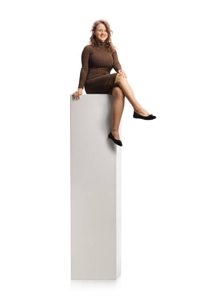 istock Young smiling female in a dress sitting on a tall white column 1301090516