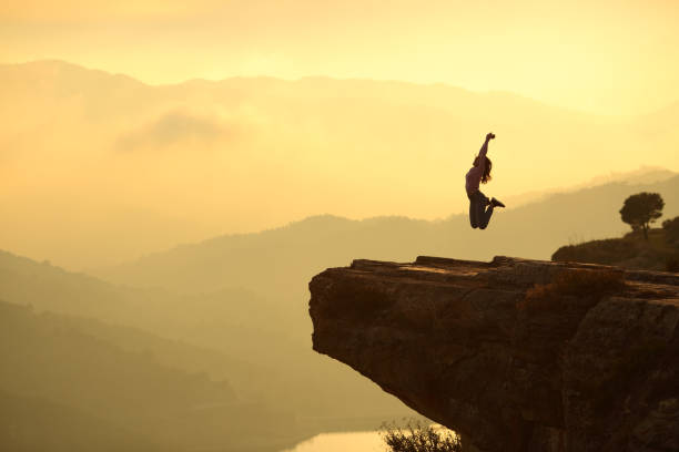 istock Woman jumping in a cliff in the mountain 1301093387