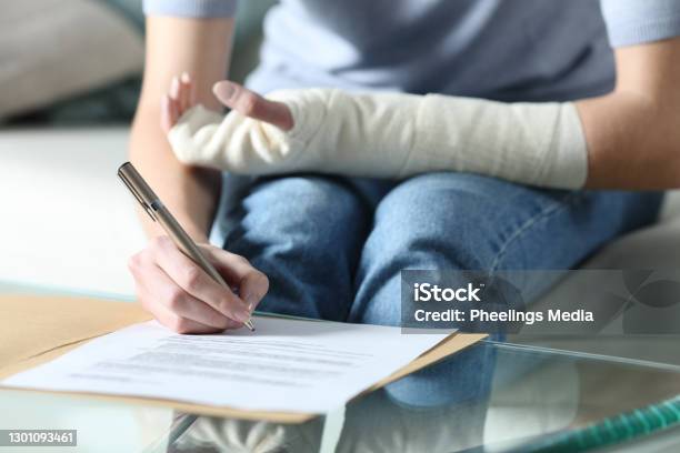 Disabled Woman With Bandaged Arm Signing Document Stock Photo - Download Image Now - Physical Injury, Insurance, Misfortune