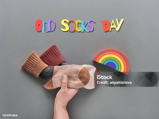 Odd Socks Day Hand Hold Pair Of Mismatched Socks Wooden Rainbow Toy Figures Social Initiative Against Bullying In School Or Workplace Promotion Design For Antibullying Campaign Stock Photo - Download Image Now