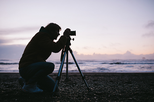 Beautiful textures and beach views of the Pacific Ocean from Washington state.  A young man photographs the scenery with his digital camera.