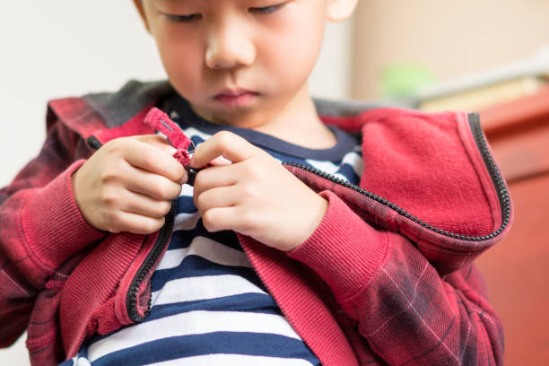 istock Cute Asian boy getting dressed for school, putting on socks, smiling with happiness to go back to school 1301102924