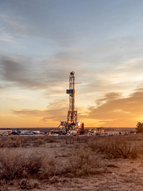 fracking rig pad mientras el sol se pone en el fondo, nuevo méxico - oil industry industry new mexico oil drill fotografías e imágenes de stock