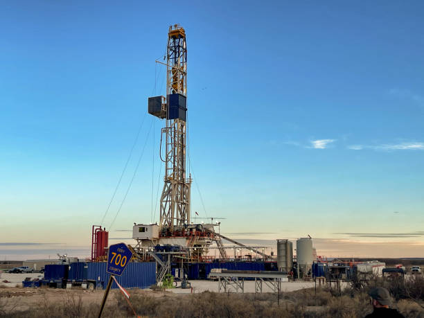 oil or gas drill fracking rig pad as the sun sets in the background, new mexico - oil industry industry new mexico oil drill fotografías e imágenes de stock