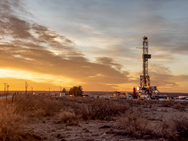 une plate-forme de fracturation de forage de pétrole ou de gaz pendant que le soleil se couche à l’arrière-plan, nouveau mexique - oil industry industry new mexico oil drill photos et images de collection