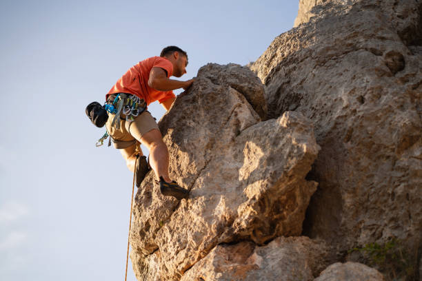 istock Low angle view of a young man climbing on the rocky mountain 1301119885