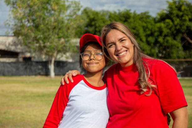 porträt der teenager-spielerin mit ihrer mutter, auf dem baseball-feld - baseball und softball nachwuchsliga stock-fotos und bilder