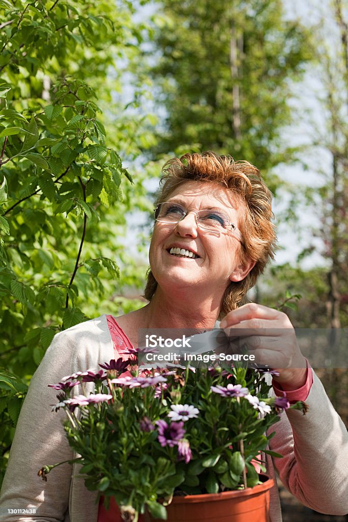 Woman looking at pot plant in nursery  55-59 Years Stock Photo
