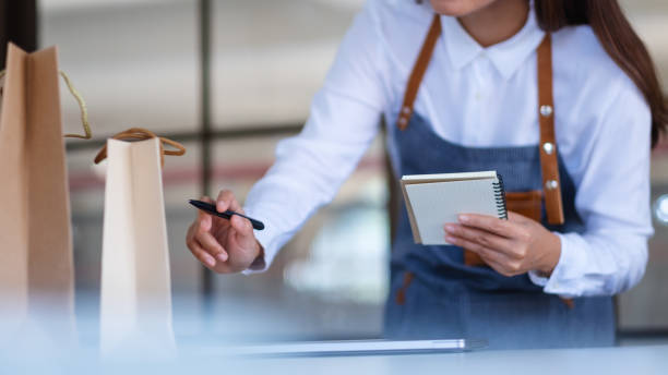 istock A young female entrepreneur with apron checking orders from customer 1301125721