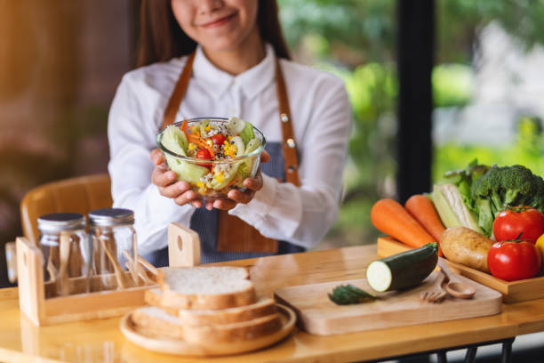 istock a female chef cooking and holding a fresh mixed vegetables salad in kitchen 1301126248