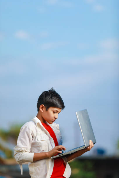 istock Cute little Indian/Asian boy studying or playing game with laptop computer 1301127302