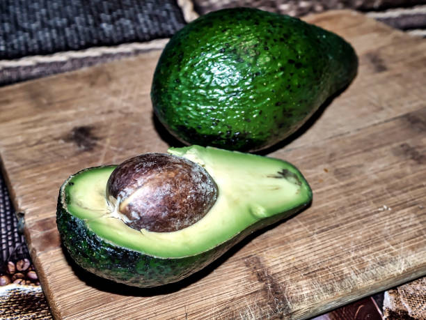 плоды авокадо разрезают пополам, ядро видно - avocado portion brown apple core стоковые фото и изображения