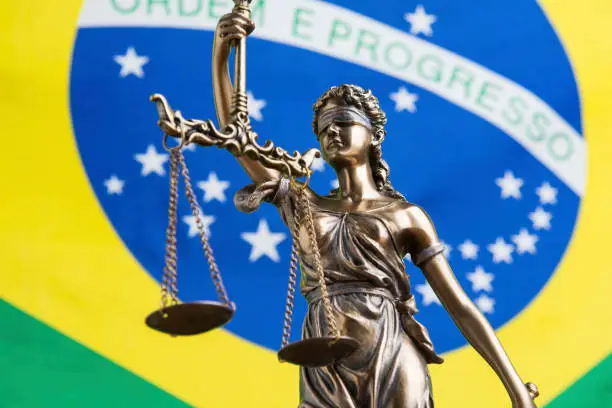 The statue of justice Themis or Justitia, the blindfolded goddess of justice against the flag of Brazil, as a legal concept