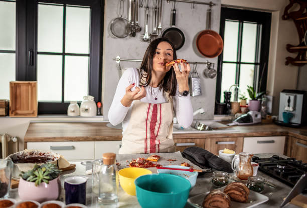 istock Woman eating pizza in the kitchen 1301132976
