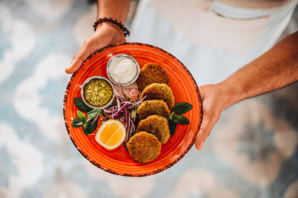 Chef Offers His Prepared Falafel Plate Flat Lay Chef Offers His Prepared Falafel Plate lebanese culture stock pictures, royalty-free photos & images