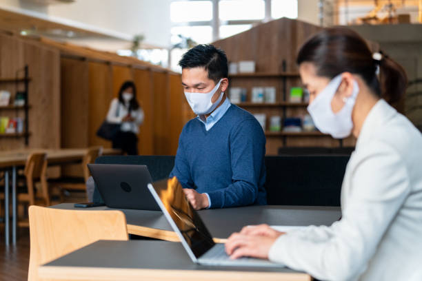 istock Group of people wearing masks working in a modern co-working office 1301137891